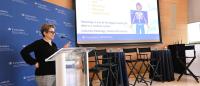 Woman at a podium next to screen
